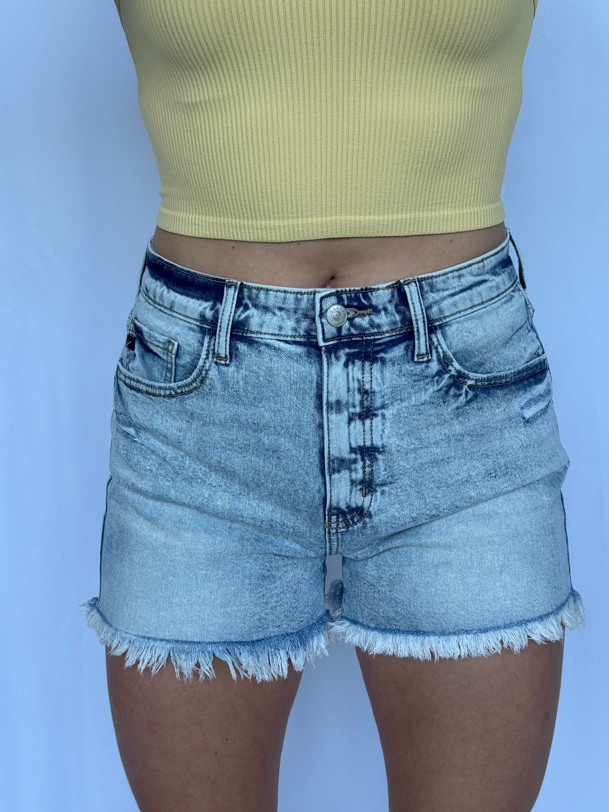 Person wearing light blue denim shorts on a white background