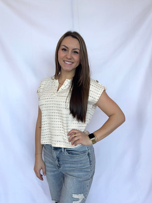 Woman wearing a patterned top and jeans against a white background