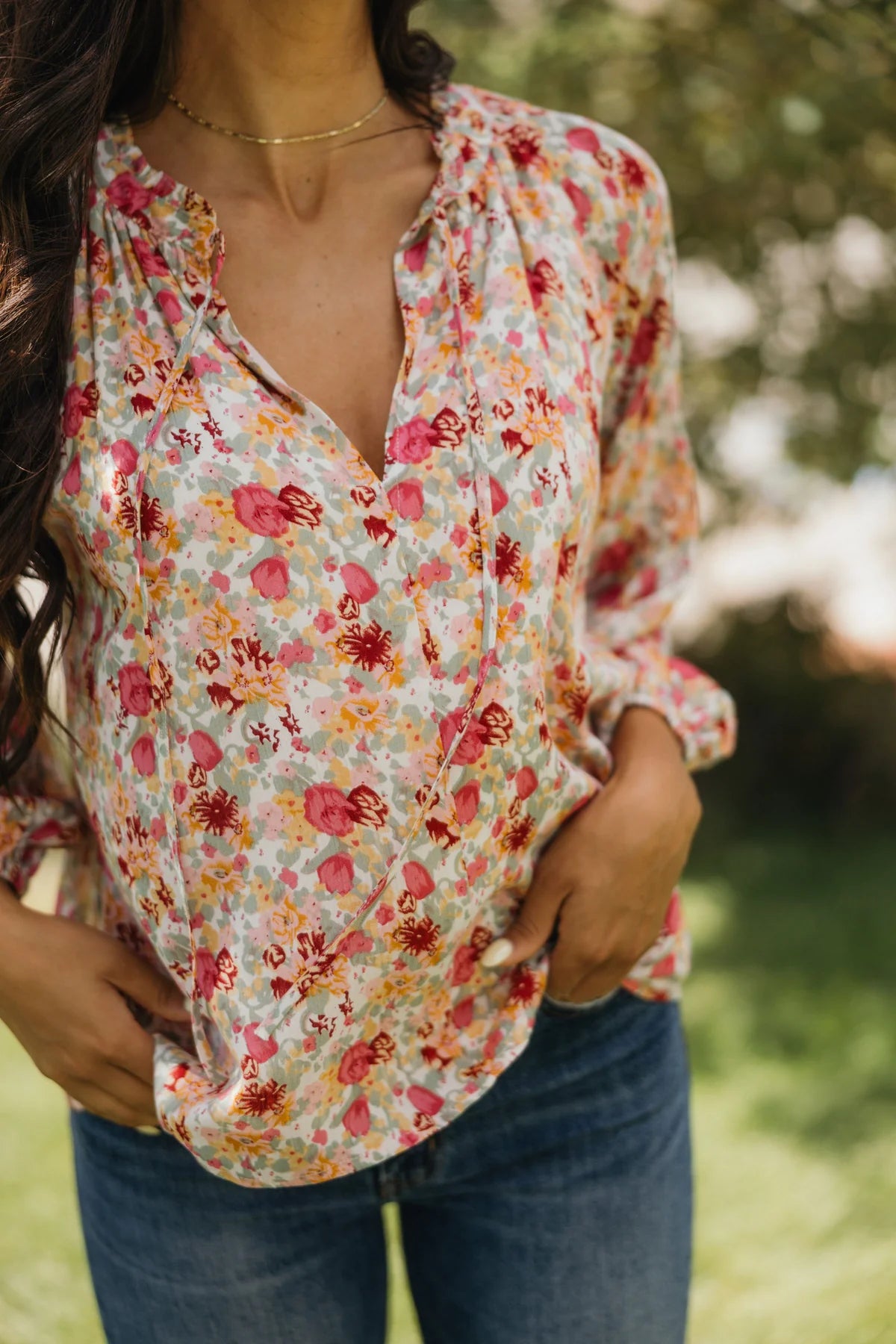 Woman wearing a floral blouse with a blurred green background