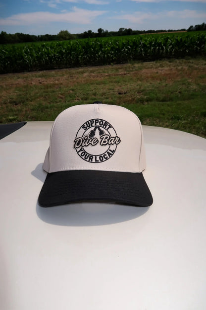 White and black cap with text on a vehicle in front of a cornfield