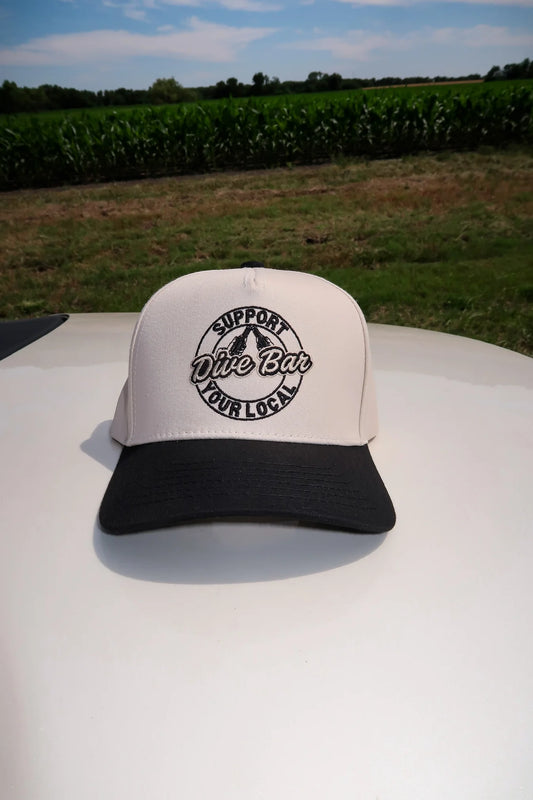 White and black cap with text on a vehicle in front of a cornfield