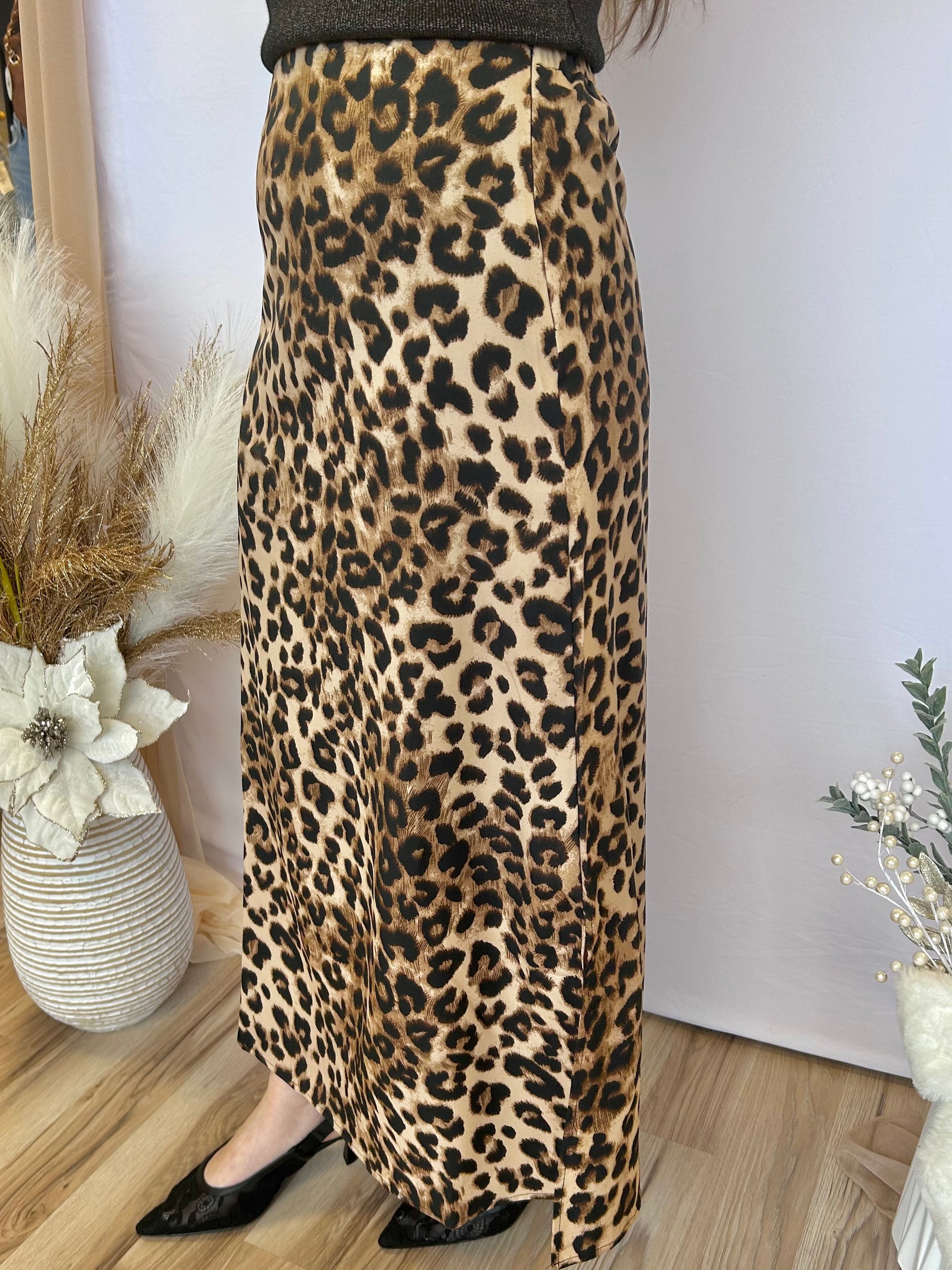 Person wearing a leopard print skirt with a plain background