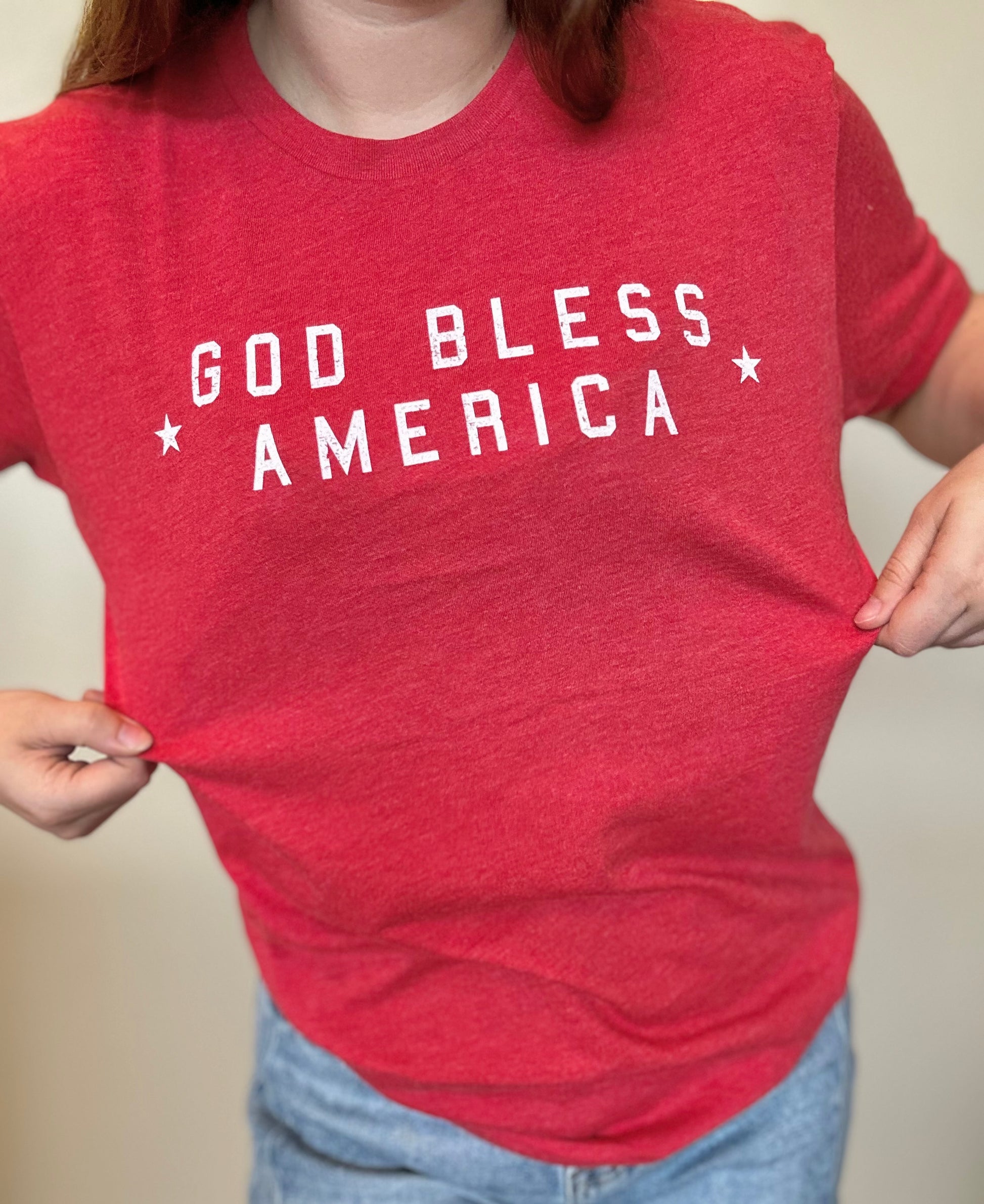 Red t-shirt with 'GOD BLESS AMERICA' text worn by a person.