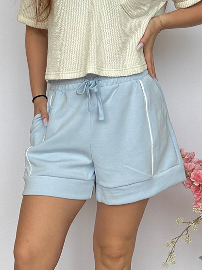 Light blue shorts worn by a person on a plain background