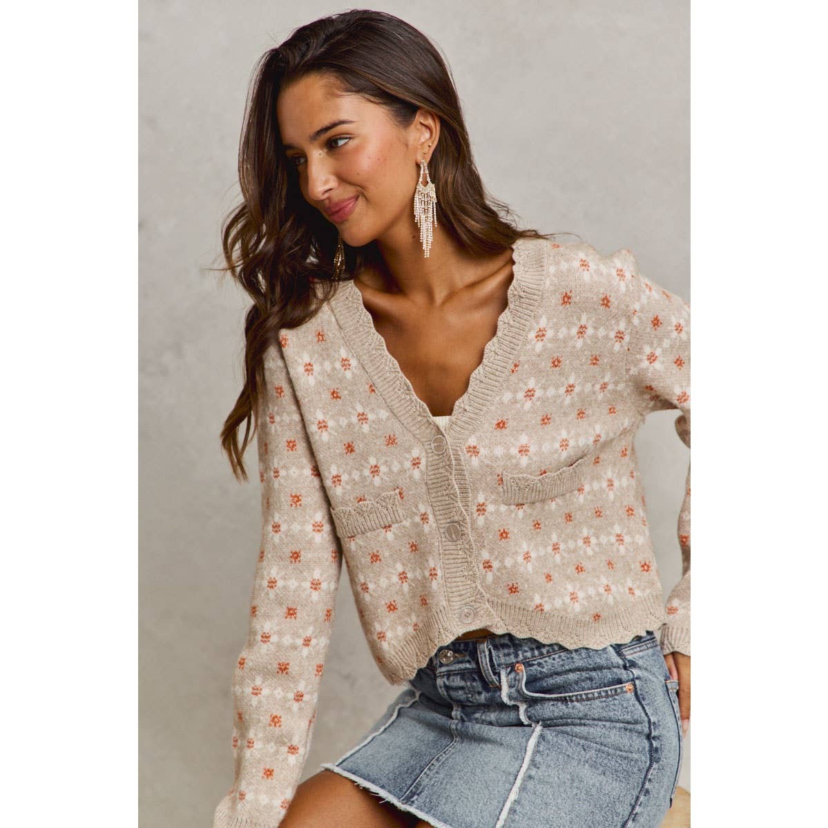 Woman wearing a floral cardigan and denim skirt against a neutral background