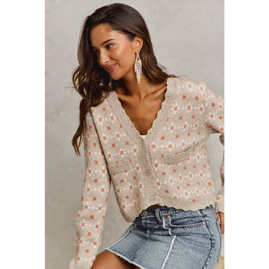 Woman wearing a floral cardigan and denim skirt against a neutral background