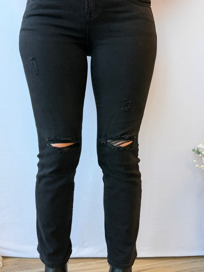 Black distressed jeans worn by a person on a light blue and white background