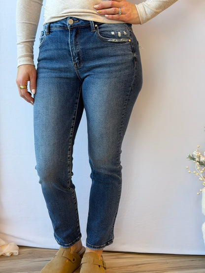 Person wearing blue jeans and tan shoes on a plain background