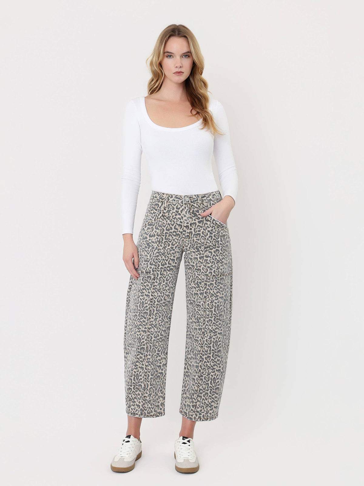 Woman wearing a white top and patterned pants on a plain background