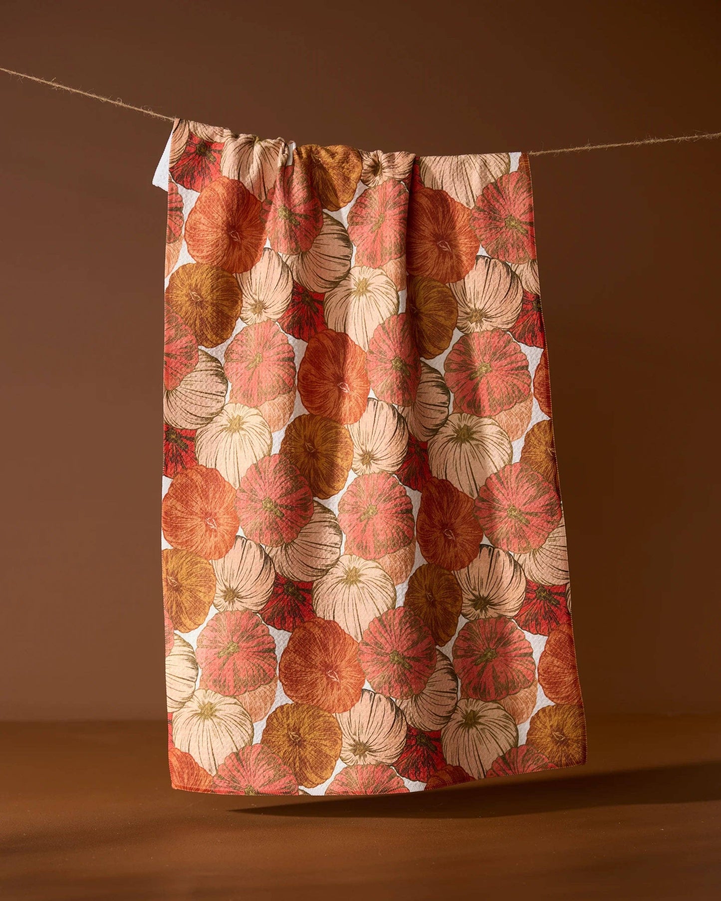 Fabric with autumnal leaf pattern hanging on a line against a brown background