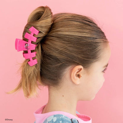 Girl with pink hair clip in her hair against a pink background